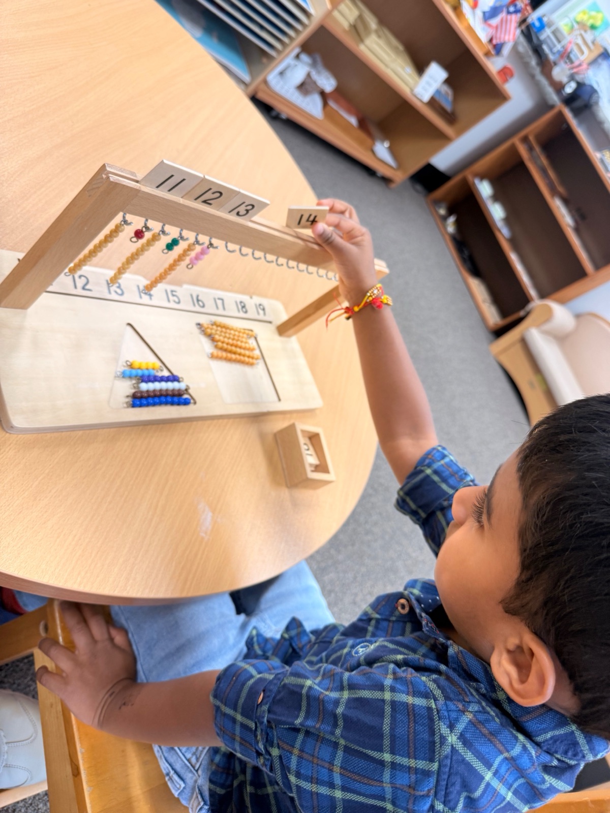 Primary boy building teen numbers with the bead hanger