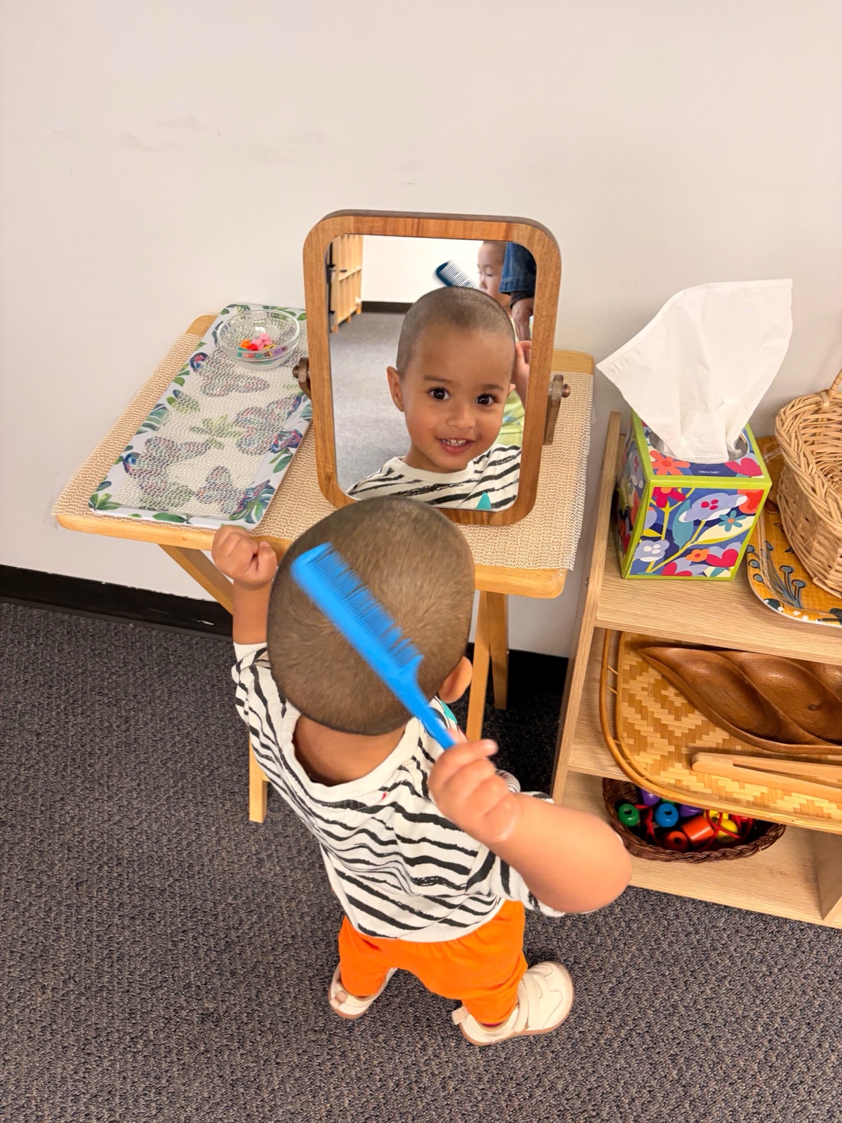 toddler combing his hair at the mirror, practical life
