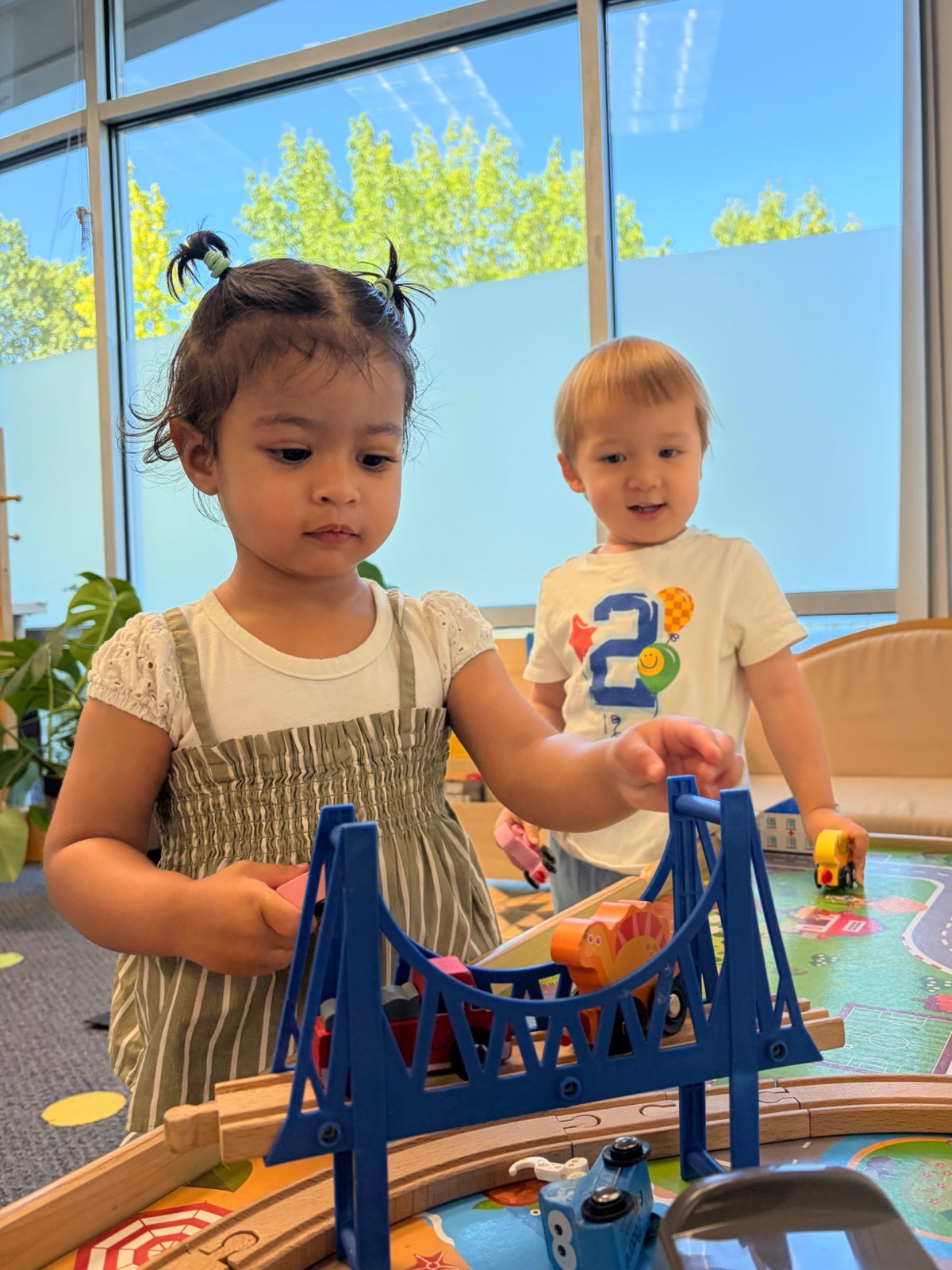 two toddlers playing together with a bridge